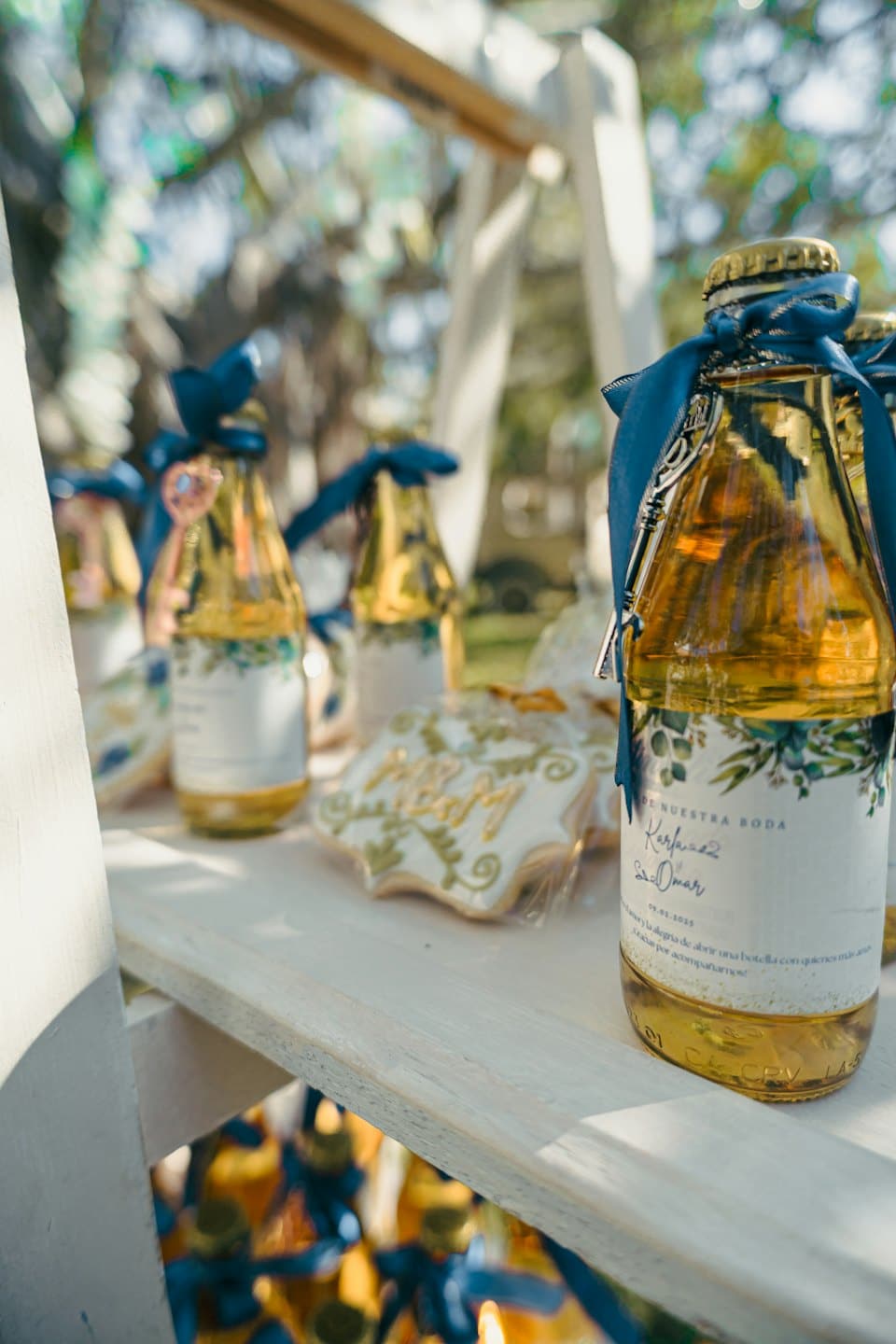 Recuerdos de boda con botellas de líquido dorado y galletas en forma de estrella en un estante.