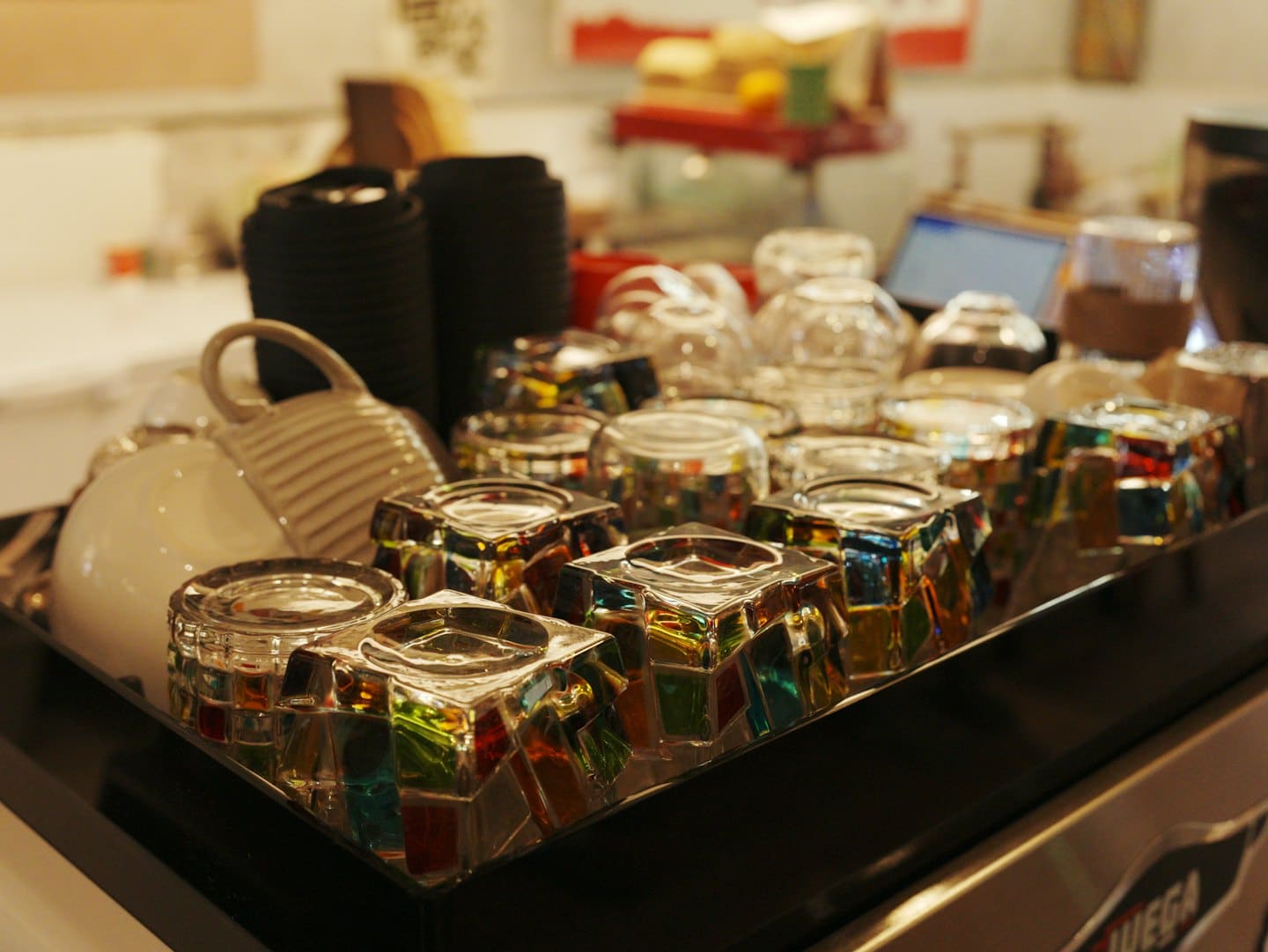 Tazas de cerámica y vasos de vidrio estampados sobre una bandeja.
