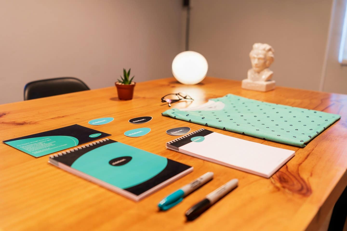 Mercancía corporativa y suministros de oficina sobre una mesa de conferencia de madera.
